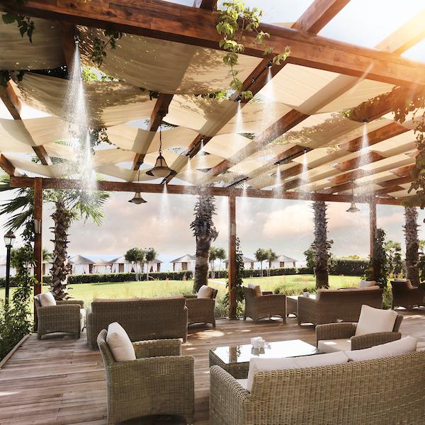 covered patio deck with several lounge chairs and misters