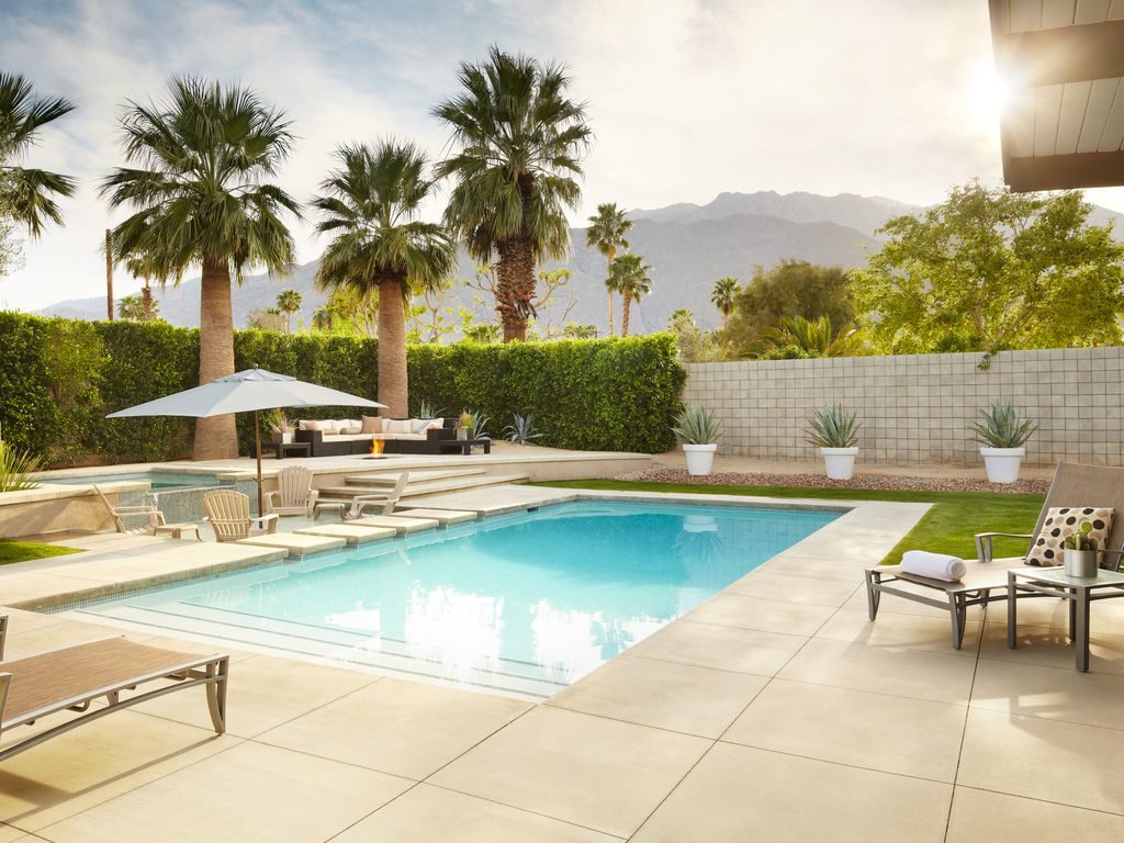 pool in california surrounded by palm trees with mountains in the background